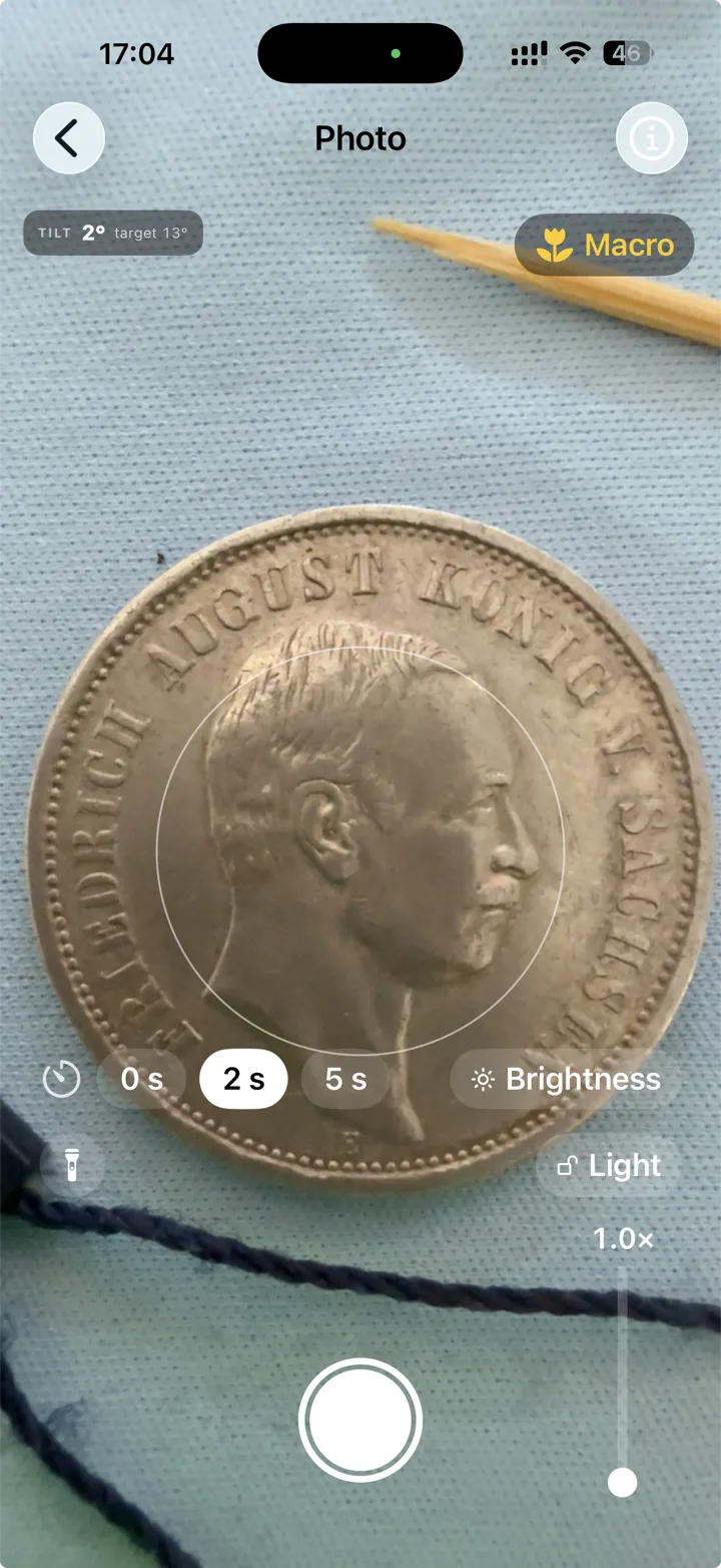 The camera screen: a coin in the centring target, a tilt readout, a macro badge and a timer